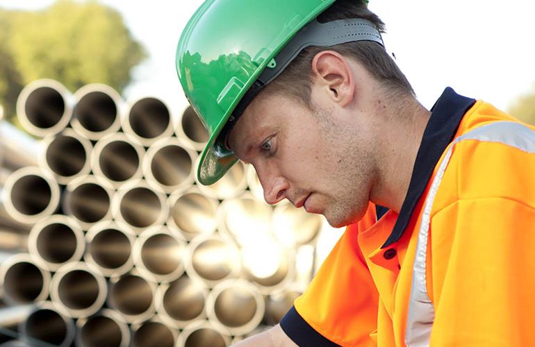 Man with hard hat in front of pipes